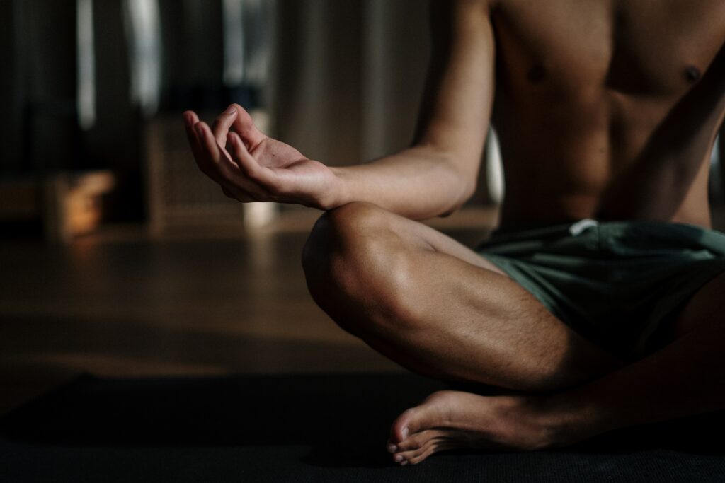 Ein Mann im Schneidersitz führt eine Meditation durch um die Schmerzen bei Bandscheibenvorfall zu reduzieren.