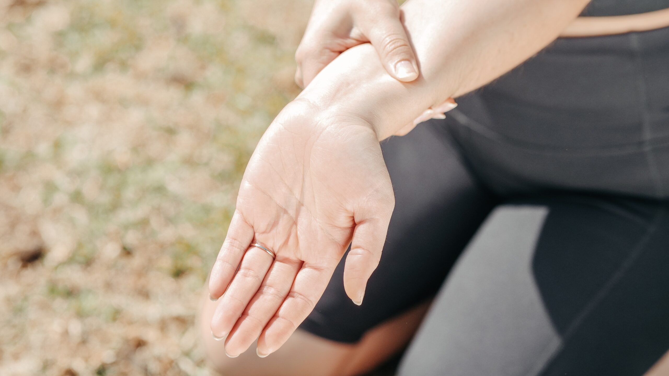 Eine Frau hält sich am Unterarm des anderen Hand fest. Möglicherweise nach Unfall und nun Vorhandensein von einem Handgelenksschmerz.