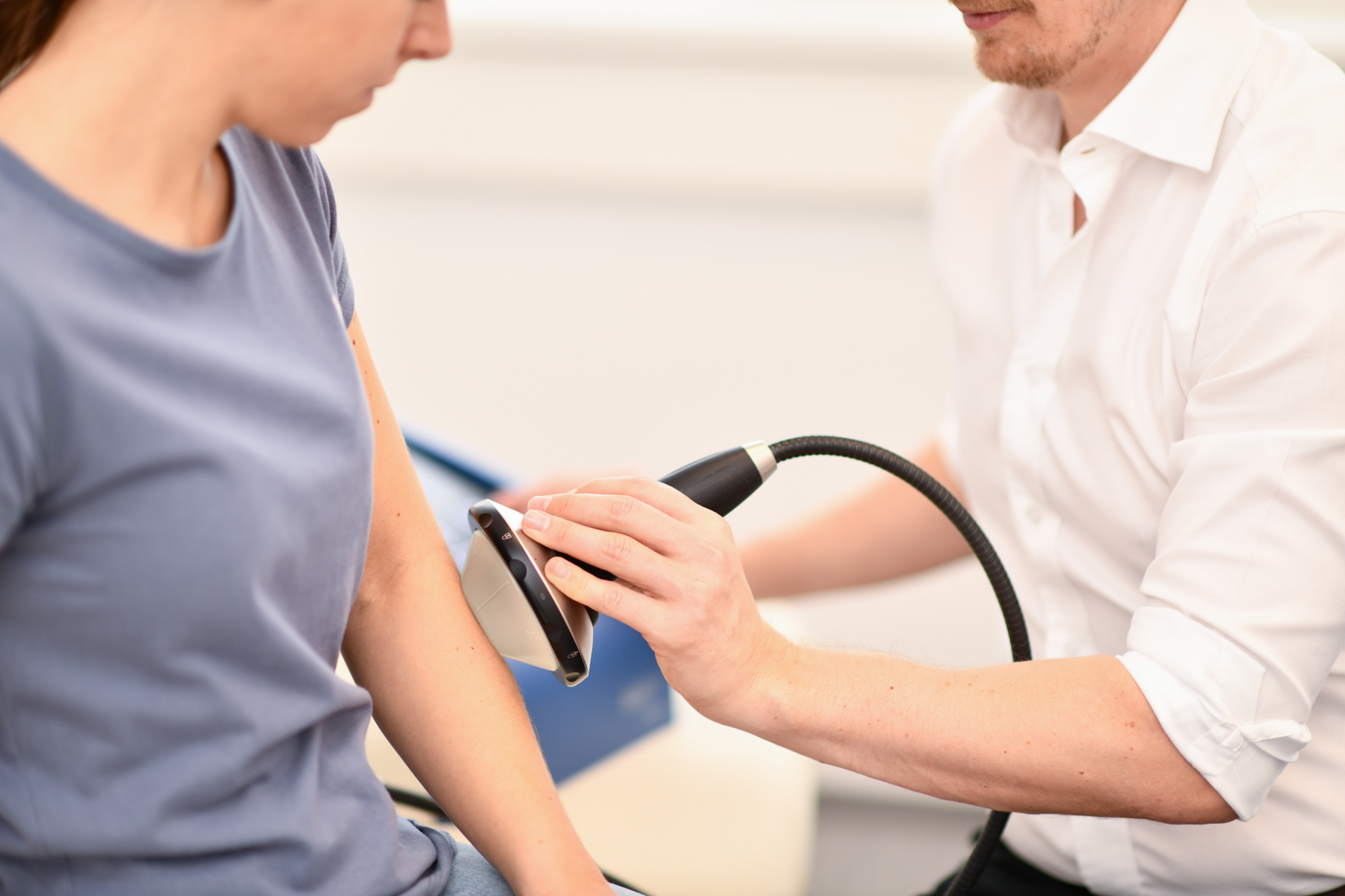 Dr Treichler führt bei einer Patientin eine fokussierte Stoßwellentherapie bei Tennisellbogen durch.