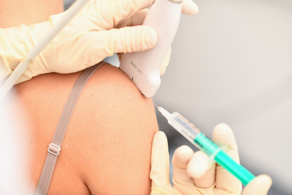 Dr. Stefan Treichler führt eine ultraschallgezielte Infiltration an der Schulter einer Patientin in seiner Praxis in Graz durch.
